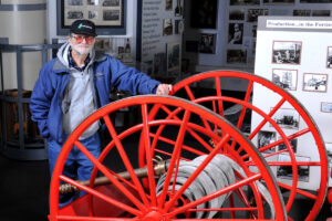 Atlas Cement Company Memorial Museum founder Edward Pany poses with a bright red firehose cart at the museum.