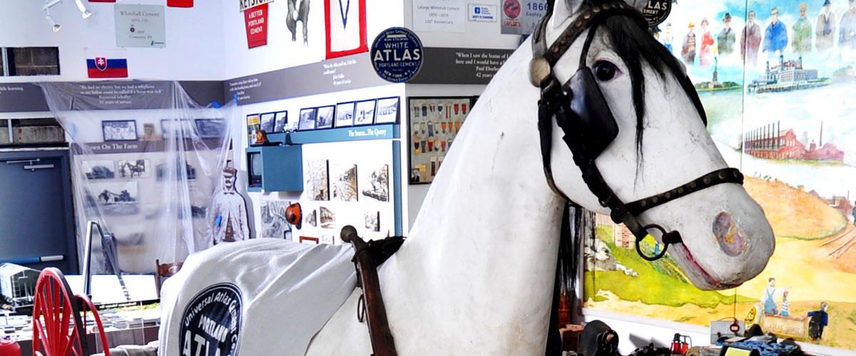 A papier-mâché horse mannequin, in front of museum exhibits and a mural.
