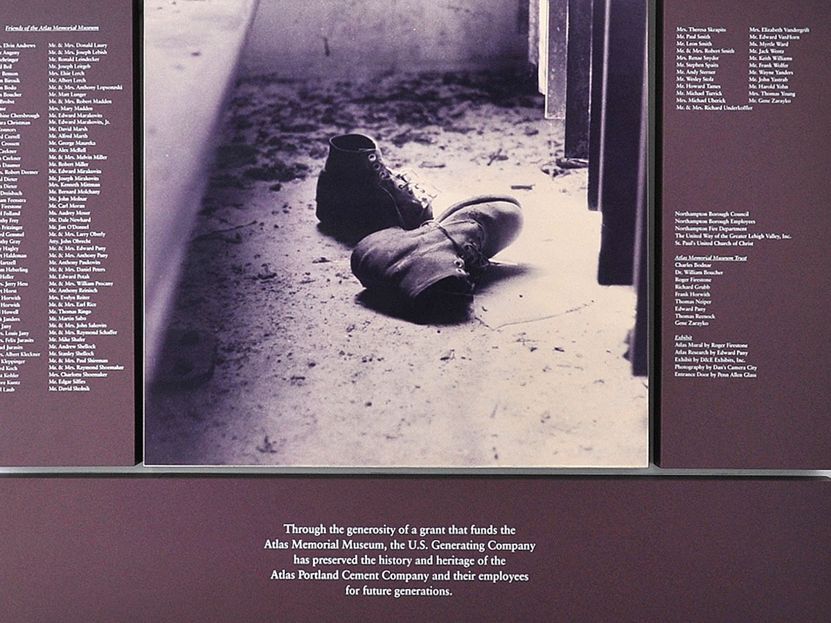 An exhibit at the Atlas Cement Company Memorial Museum features a black-and-white historic photo of an abandoned pair of work boots.