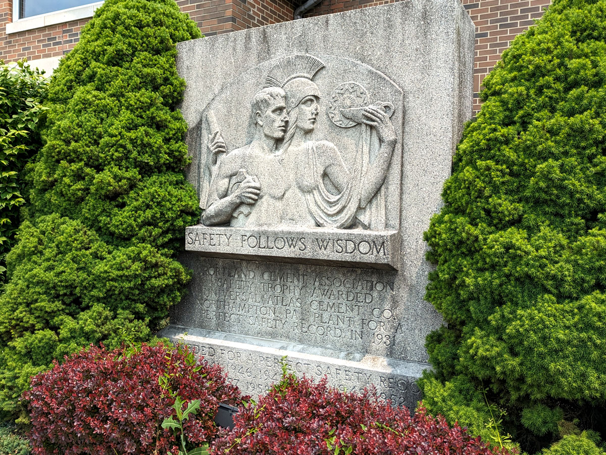 Stone monument with a relief sculpture of a helmeted woman with an oil lamp leading a man, and the words 