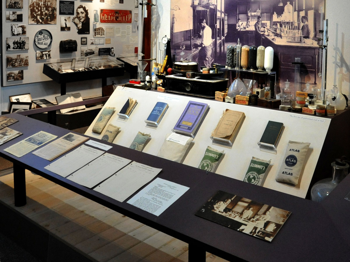 A museum exhibit on the Atlas Cement Company's lab includes rock samples in glass cylinders, glass containers for chemical tests, and an assortment of books, photos and company records.